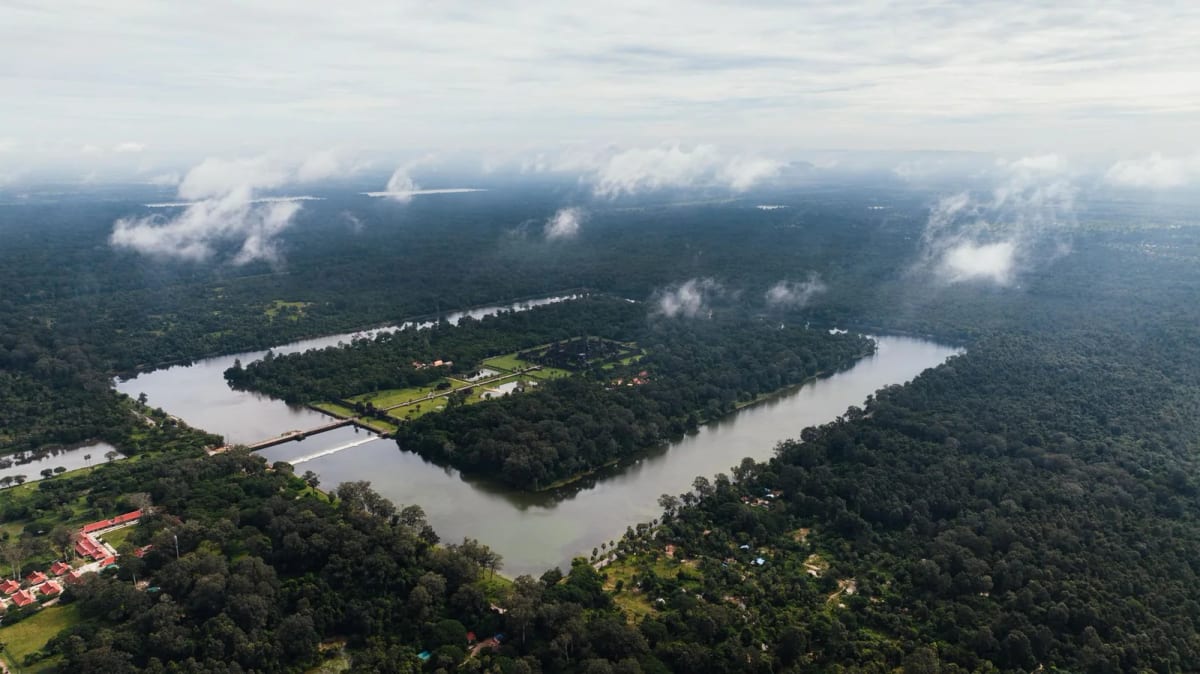 Vue aérienne d'Angkor Wat entouré de ses douves rectangulaires et de la forêt, sous des nuages bas