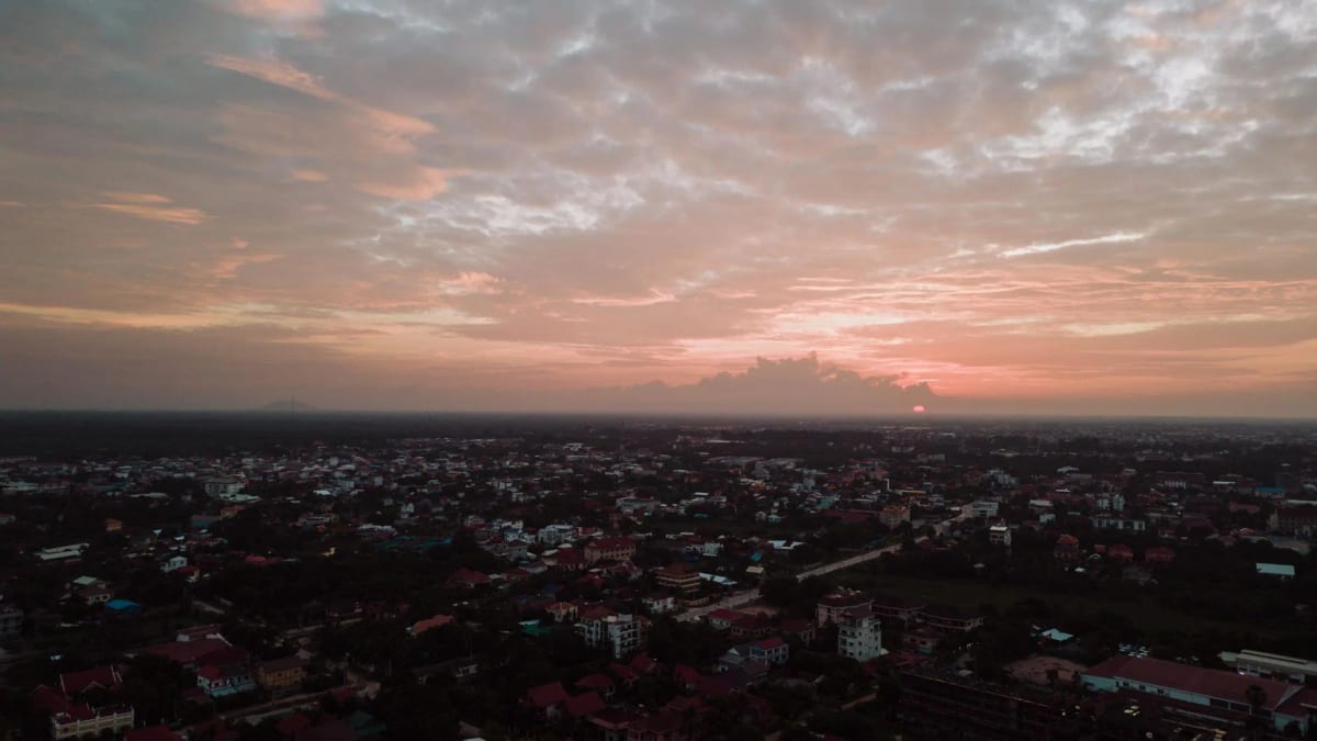 Vue aérienne d'une ville cambodgienne aux toits de tuile rouge au coucher du soleil