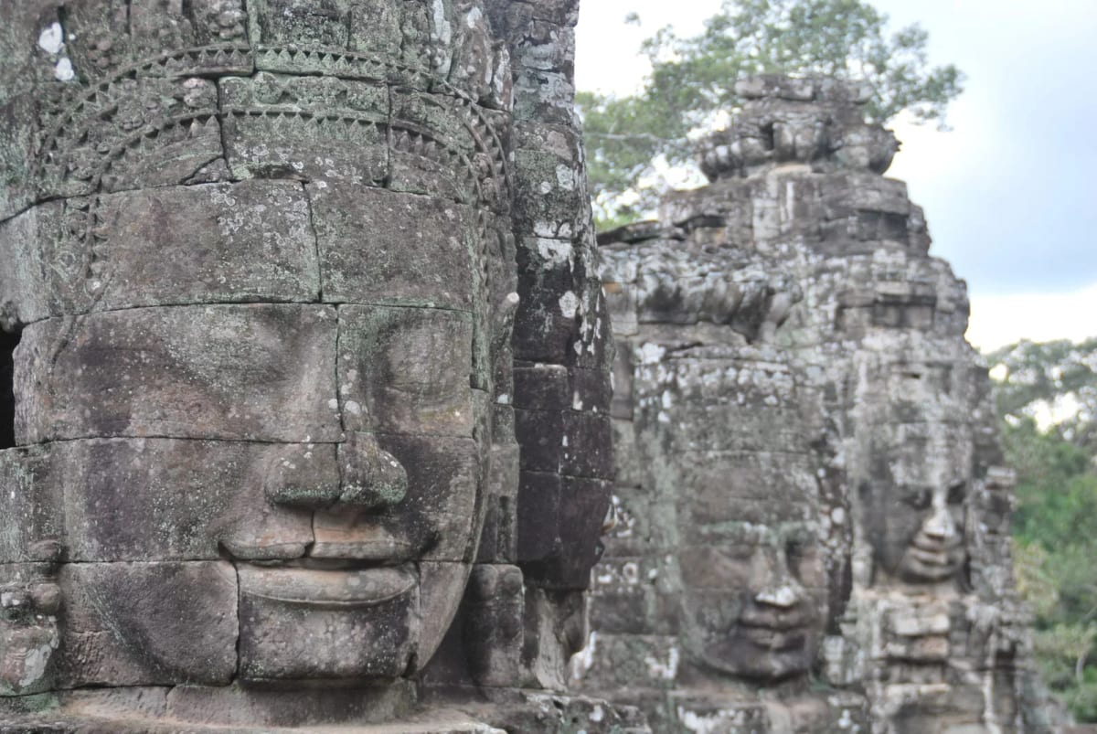 Visages de pierre sculptés sur les tours du temple du Bayon, à Angkor Thom